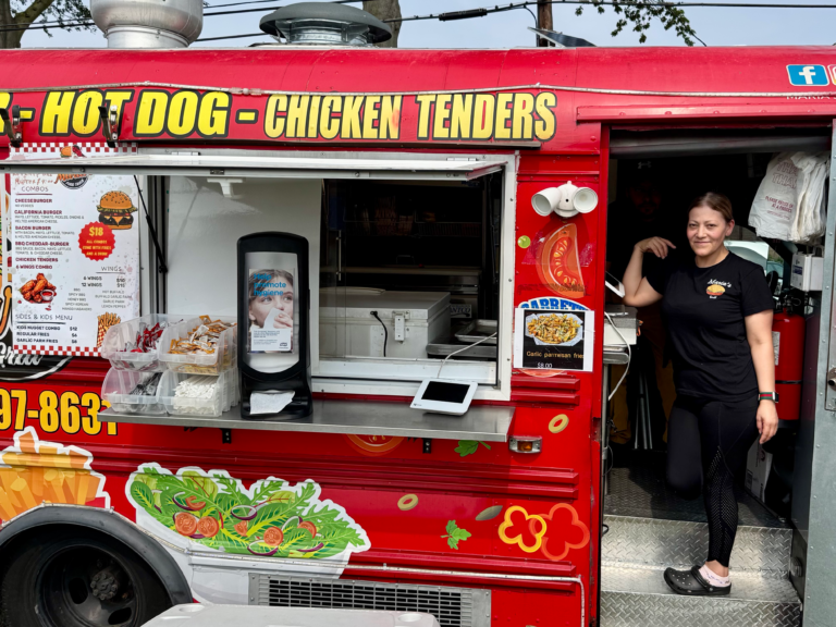 A vendor smiles at the Mayor’s Cup food truck serving hot dogs, tenders, and burgers in Rahway.