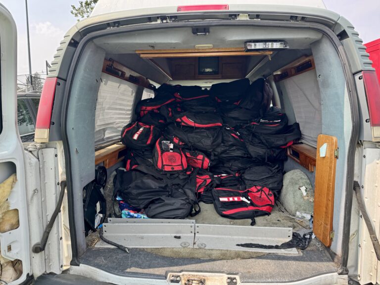 Dozens of red-and-black backpacks stacked in the back of a van for giveaway at the Mayor’s Cup in Rahway.