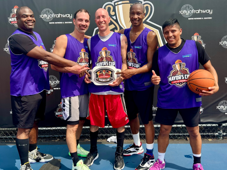 SPF Dads basketball team poses with belts after winning the 30+ division at the Mayor’s Cup tournament in Rahway.
