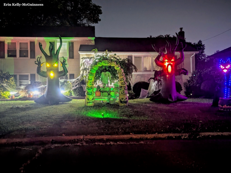 House in Rahway with glowing purple and green Halloween lights and hanging ghosts on the porch.