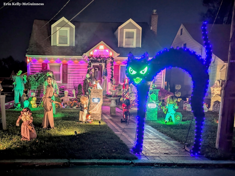 Inflatable pumpkin and ghost display on a Rahway lawn lit by orange string lights at dusk.