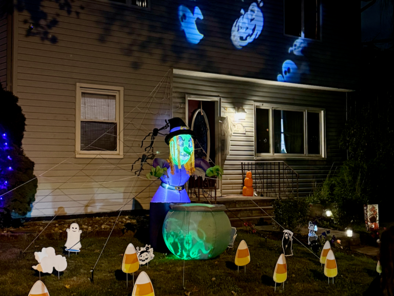 Halloween night scene in Rahway showing a front porch with cobwebs, jack-o’-lanterns, and eerie purple lighting.