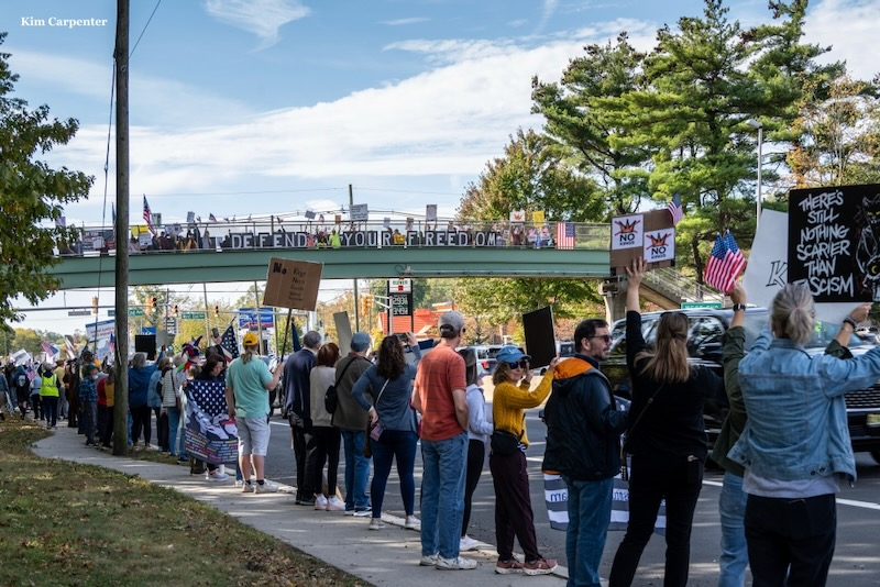 Protesters hold “Defend Your Freedom” banners across a bridge in Plainfield during the No Kings demonstrations.