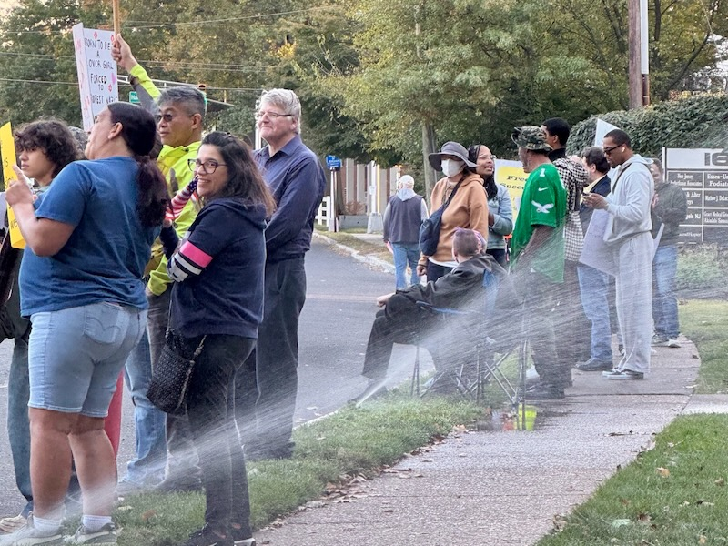 Protesters along St. Georges Avenue in Rahway continue rallying despite lawn sprinklers spraying water during the “No Kings” protest.