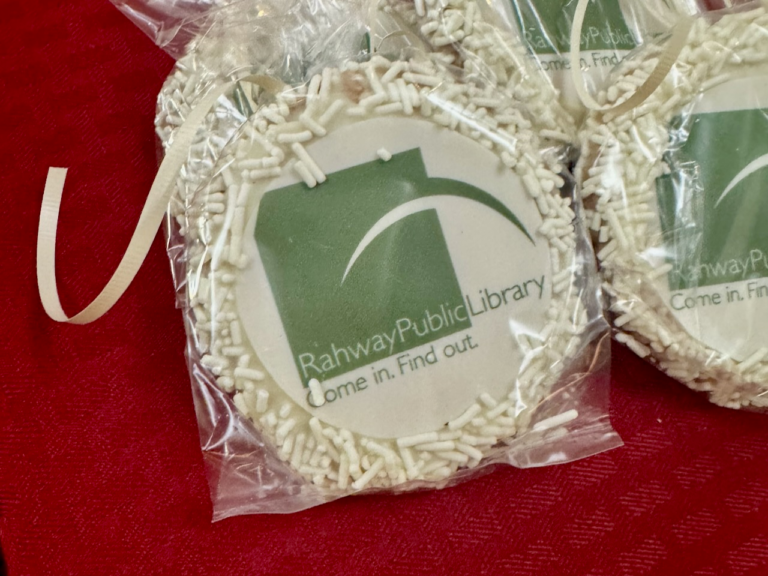 Close-up of Rahway Public Library cookies with the library logo and white sprinkles packaged for guests.